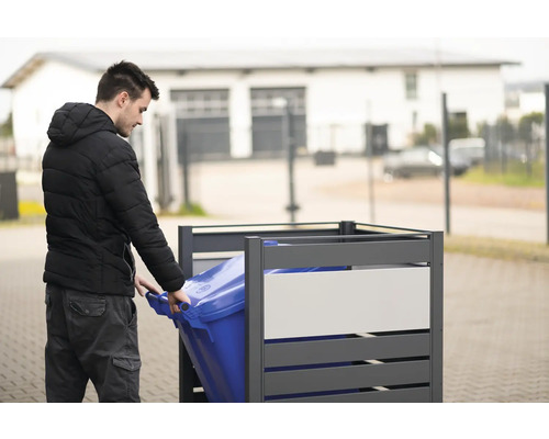 Mann schiebt blaue Mülltonne in graue Mülltonnenbox