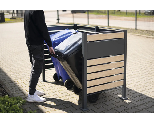 Personne poussant une poubelle dans un coffre à ordures en métal et en bois