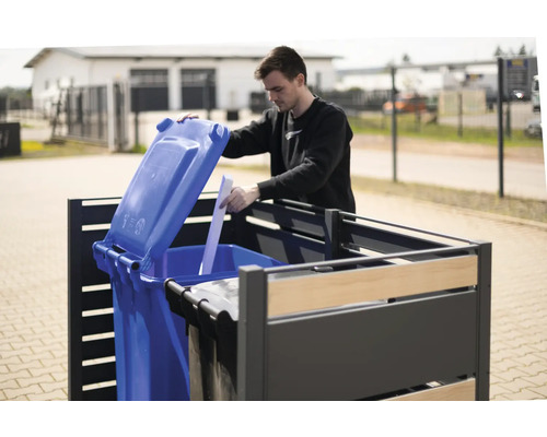 Un homme ouvre une poubelle bleue dans un coffre à poubelles