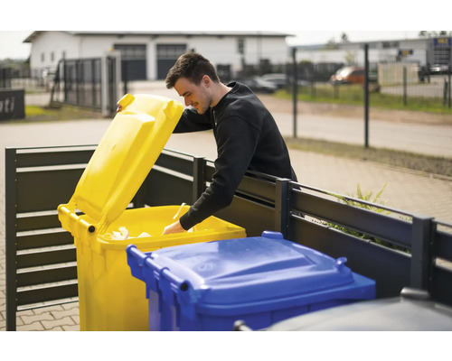 Un homme jette du papier dans une poubelle jaune
