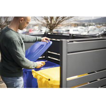 Homme ouvrant un coffre à poubelles avec deux poubelles