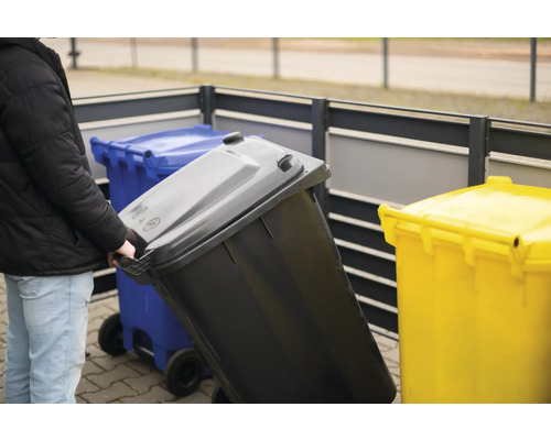 "Une personne pousse une poubelle à roulettes 