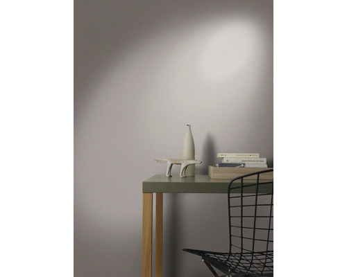 Arrangement décoratif sur une table avec sculpture, vase et livres dans une pièce lumineuse