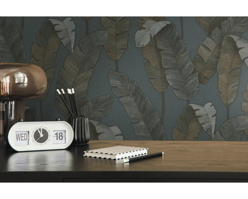 Gros plan d''une table avec une horloge, un carnet et du papier peint à motifs de feuilles