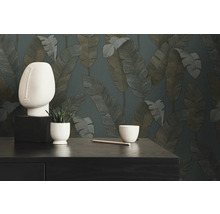 Scène décorative avec une sculpture de tête abstraite, une plante en pot, un crayon et un bol sur fond de papier peint à motifs de feuilles
