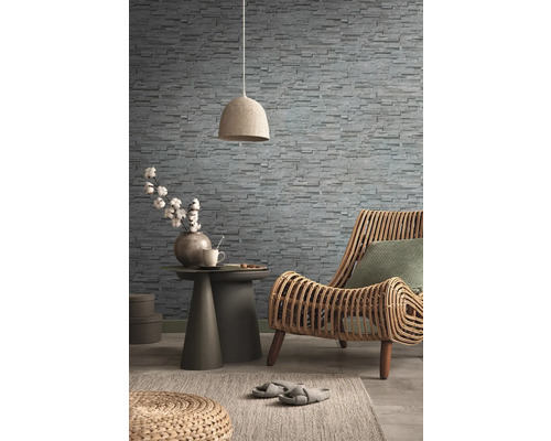 Salon décoratif avec fauteuil en rotin, papier peint en pierre, table d''appoint, lampe et tapis pour une ambiance chaleureuse