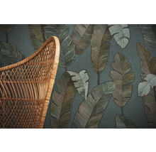 Gros plan d''un papier peint à motifs de feuilles à côté d''une chaise en osier