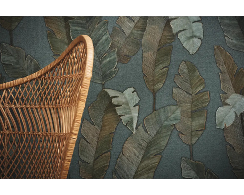 Gros plan d''un papier peint à motifs de feuilles à côté d''une chaise en osier