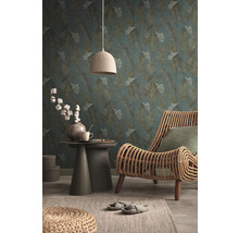 Salon avec papier peint à motif de feuilles, fauteuil en rotin, table d''appoint et lampe en textile pour une ambiance chaleureuse