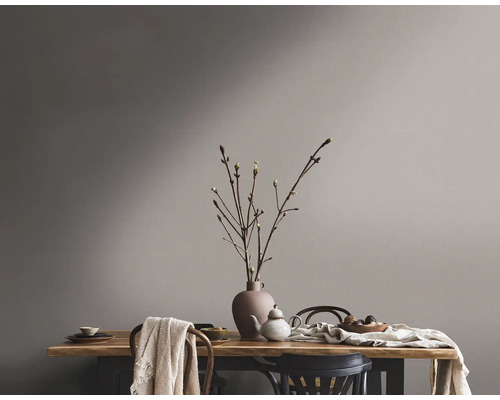 Tischdekoration mit Geschirr und Vase vor gestrichener Wand