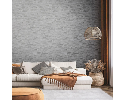 Salon avec canapé, coussins décoratifs et papier peint mural à l''aspect pierre.