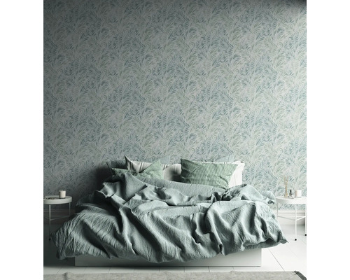 Chambre avec lit devant un mur recouvert de papier peint à motifs de feuilles