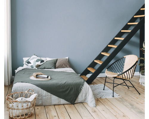 Helles Schlafzimmer mit Bett, Leiter, Stuhl und Wäschekorb auf Holzboden