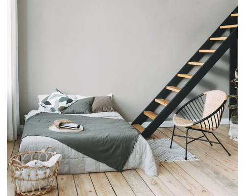 Schlafzimmer mit Bett, Leiter, Korbsessel und Wäschekorb