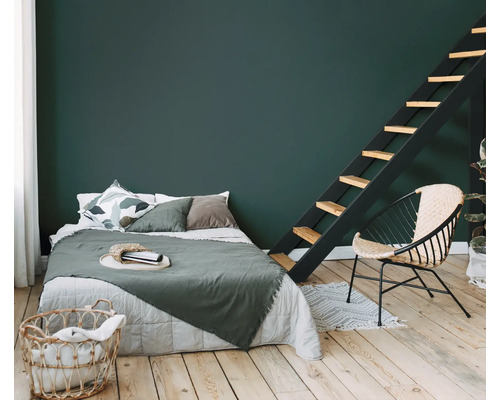Chambre à coucher avec lit, échelle et fauteuil en rotin sur plancher en bois