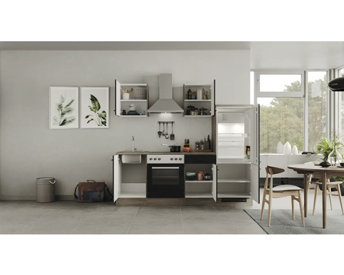 Cuisine complète avec évier, cuisinière, four, hotte aspirante, éléments hauts et réfrigérateur dans une cuisine lumineuse.