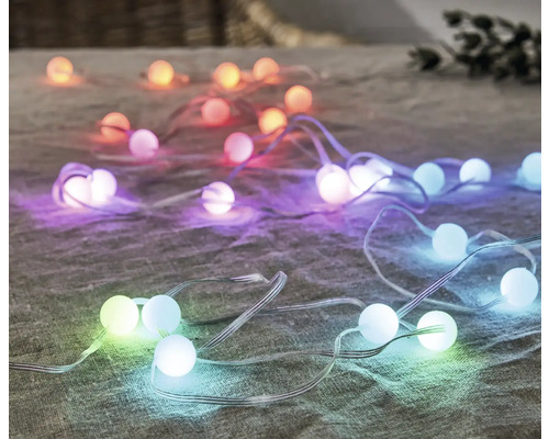 Dekorative Lichterkette mit farbigen Kugeln auf Stoffuntergrund