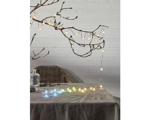 Dekorative Lichterkette mit Kugeln auf einem Tisch und an einem Ast