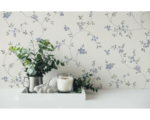 Papier peint décoratif à motifs floraux dans une pièce lumineuse, combiné à une bougie et à des plantes vertes.