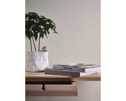 Dekoratives Interieur mit gemusterter Tapete, Pflanze und Büchern auf einem Holztisch