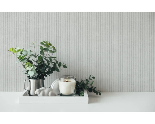 Décoration avec eucalyptus, bougie et figurine décorative sur un plateau devant un papier peint rayé