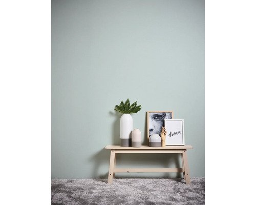 Scène décorative avec banc, vases et tableaux devant un mur