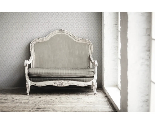 Canapé vintage avec cadre en bois et revêtement rayé devant un papier peint à motifs