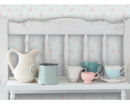Scène décorative avec divers cruches et tasses sur une étagère blanche devant un papier peint floral.