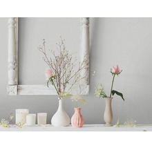 Scène d''intérieur avec décorations florales, bougies et cadre photo devant un papier peint à motifs