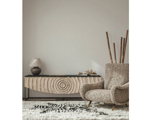 Intérieur de salon avec fauteuil à motifs, buffet, lampe et tapis pour une ambiance cosy.