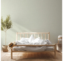 Chambre claire avec lit, plante et papier peint rayé