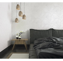 Chambre avec lit, table de chevet, lampe et papier peint à motifs