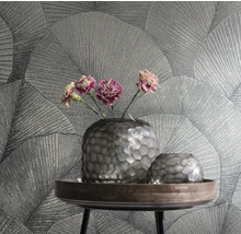 Deux vases et des fleurs sur une table devant un mur avec du papier peint à motifs de feuilles.