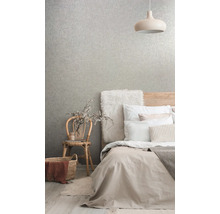 Chambre avec lit, lampe, chaise et papier peint à motifs pour une ambiance claire et organisée.