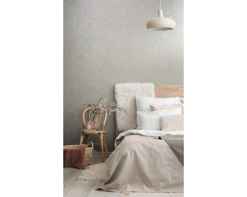 Chambre avec lit, lampe, chaise et papier peint à motifs pour une ambiance claire et organisée.