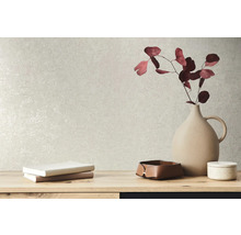 Dekorative Elemente wie eine Vase, Bücher und Schalen auf einem Tisch vor einer strukturierten Wand.