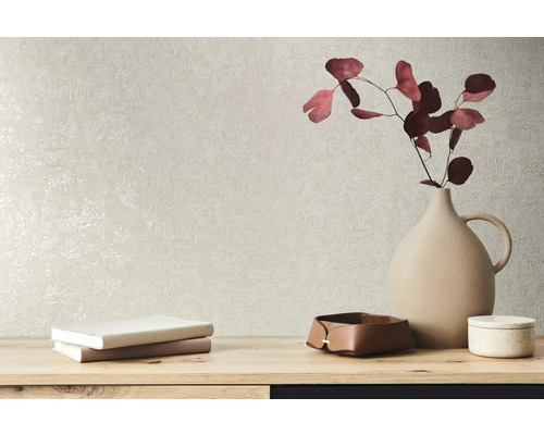 Dekorative Elemente wie eine Vase, Bücher und Schalen auf einem Tisch vor einer strukturierten Wand.