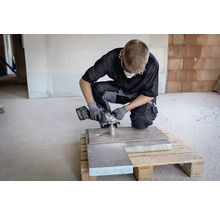 Handwerker mit Akku-Winkelschleifer bei der Arbeit an einer Platte