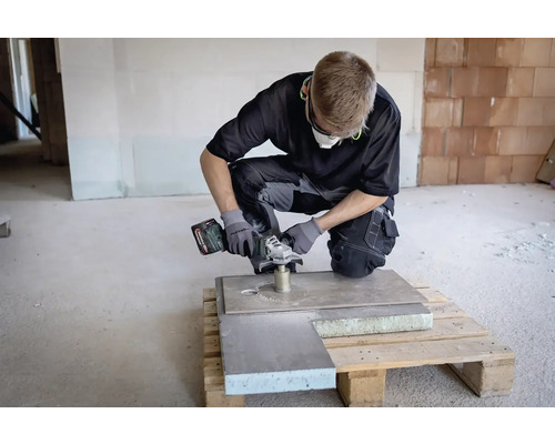 Handwerker mit Akku-Winkelschleifer bei der Arbeit an einer Platte