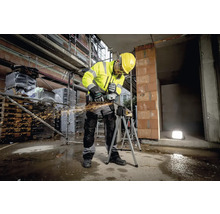 Ein Bauarbeiter in Arbeitskleidung benutzt einen Winkelschleifer auf einer Baustelle
