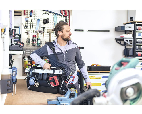 Mann mit Werkzeugtasche in Werkstatt