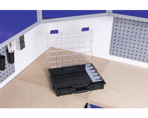 Boîte à outils ouverte avec compartiments sur un établi