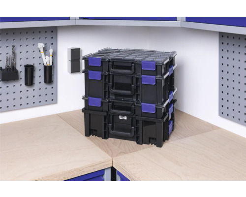 Pile de boîtes à outils noires avec fermeture bleue sur un établi