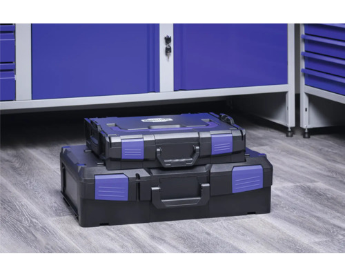 Zwei schwarze Werkzeugkoffer unterschiedlicher Größe gestapelt vor einem blauen Werkzeugschrank.