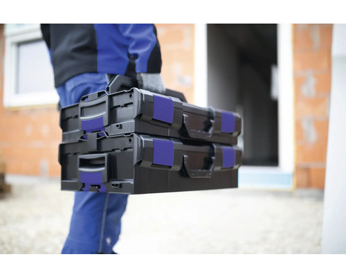 Une personne porte deux boîtes à outils noires.