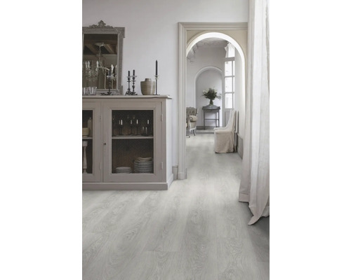 Pièce lumineuse avec plancher en bois clair, commode et passage vers une autre pièce