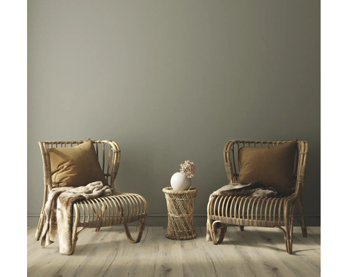 Zwei Rattansessel mit Kissen und Decken sowie ein Beistelltisch mit Blumenvase in einem hellen Raum.