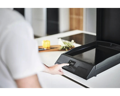 Une personne utilise une plaque de cuisson électronique dans une cuisine