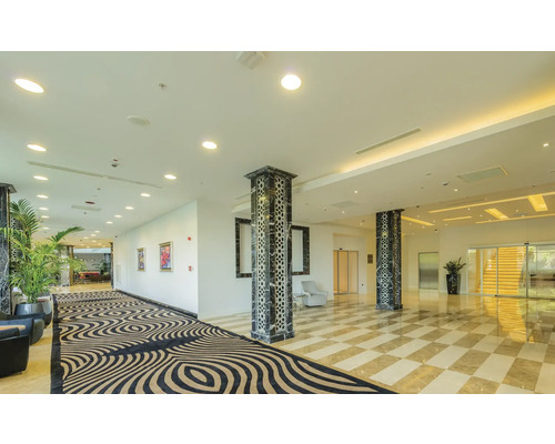 Hall d''accueil lumineux avec moquette à motifs, piliers en marbre et sol en damier
