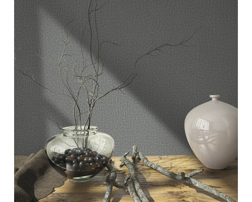 Dekorative Szene mit Vase, Ästen und Textiltuch auf Holztisch vor grauer Wand